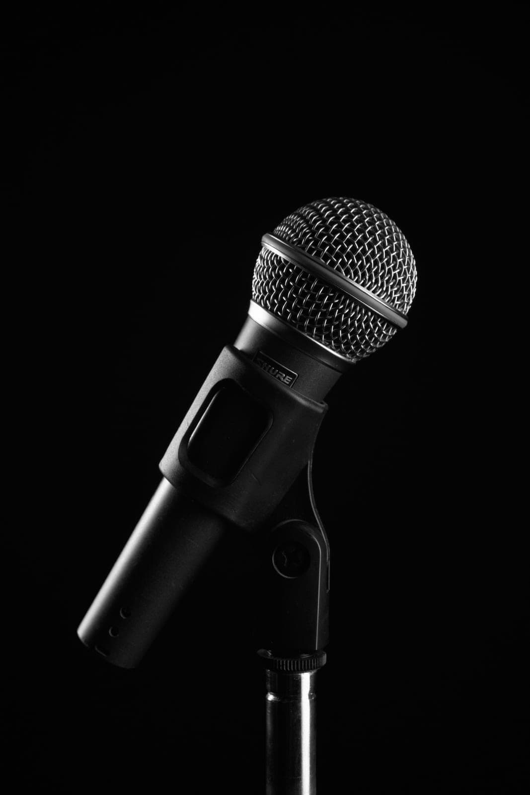 A microphone on a stand lit against a dark background