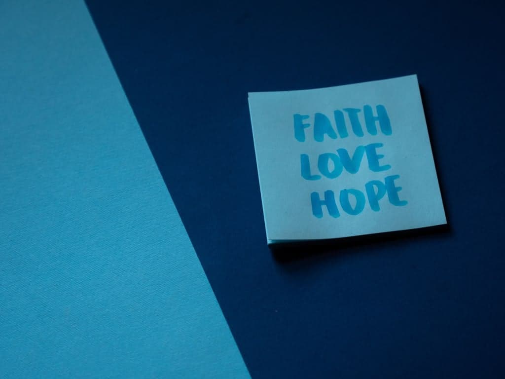 A sticky note reading "Faith, Love, Hope" against a deep blue background