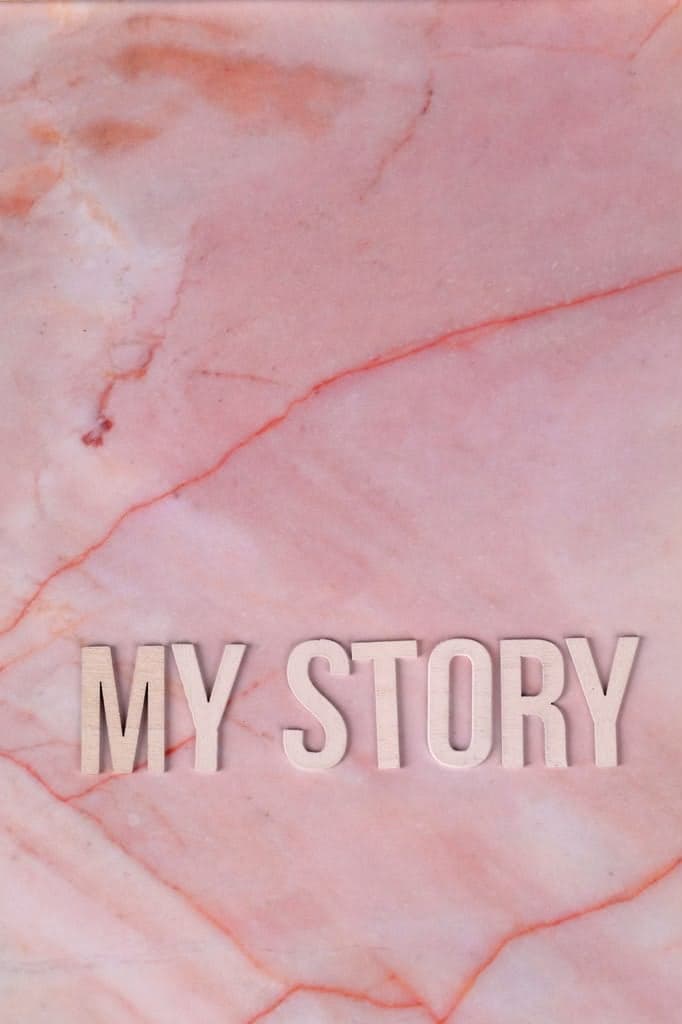 The words "MY STORY" spelled in wooden letters on pink marble